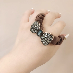 Detail of a vintage bow hair tie with grey rhinestones and brown pleated fabric band