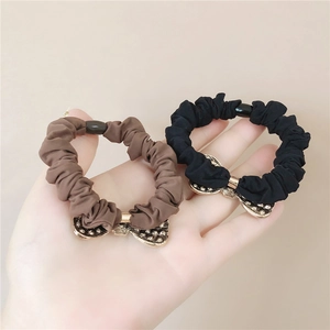 Detail of high-elasticity scrunchies in black and brown with golden metal bows