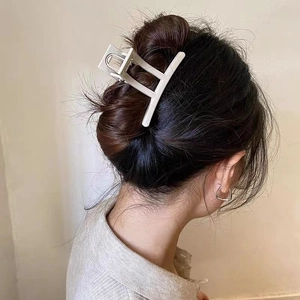 Gros plan d'une pince à cheveux mate crème tenant une coiffure relevée élégante