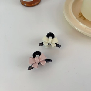 Close-up of mini acrylic bow hair clips in pink and beige with glossy black finish
