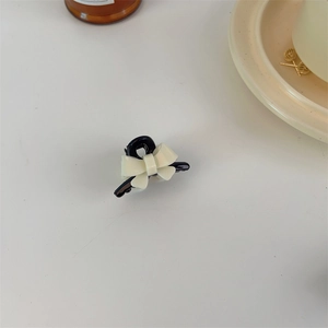 Close-up of a mini acrylic bow hair claw clip in contrast black and white resin finish