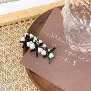 Vintage pearl hair clip with black ribbon bow and heart pearls on a wooden tray