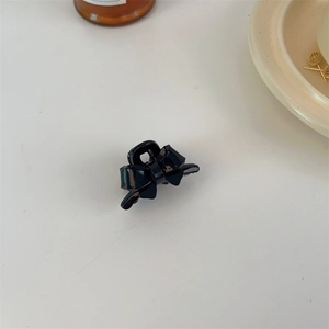Close-up of a small black acrylic bow hair claw clip with a glossy polished finish