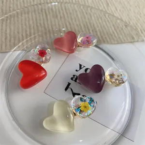 Détail de barrettes à cheveux en résine en forme de cœur avec fleurs séchées et paillettes