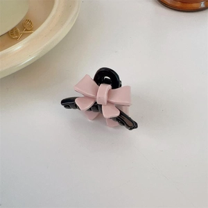 Pink and black acrylic bow hair claw clip for women on a minimal white background
