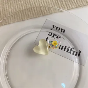 Détail d'une pince à cheveux cœur jaune crème avec de vraies fleurs séchées et paillettes