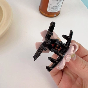 Pink flower-shaped acrylic hair claw clip with black teeth shown in hand