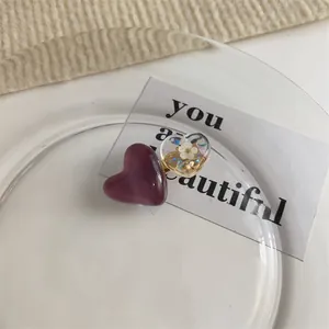 Détail de barrettes à cheveux en résine en forme de cœur avec fleurs séchées et paillettes