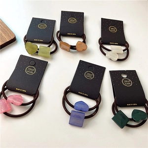 Detailed view of six colorful geometric resin hair ties with heart and square charms