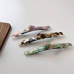 Close-up of three marble-textured acetate hair barrettes with twisted knot details