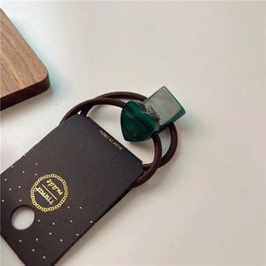 Close-up of deep green heart and square resin charms on a durable elastic hair tie