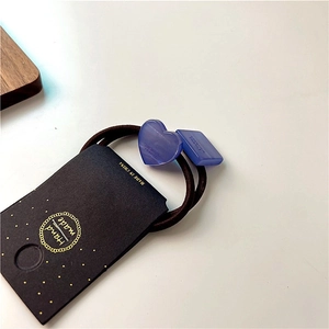 Detail of blue resin heart and square charms on a high-elastic brown hair tie for women