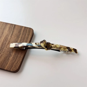 Detail showing marble texture acetate twist knot hair clip with silver spring fastener