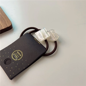 Detail view of square and heart hair ties with shell luster finish and handmade tag