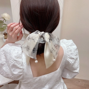Dettaglio dell'elastico in organza floreale con eleganti ciondoli di perle sulla coda