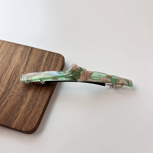 Close-up of marble texture acetate hair clip with knot design and metal spring buckle
