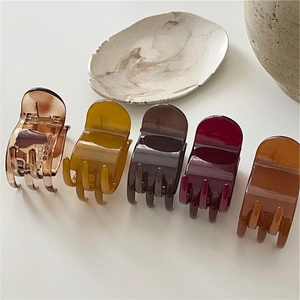 Close-up of five small hair claws in amber, burgundy and brown glossy resin finish
