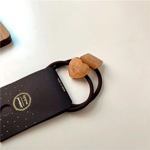 Detail of amber tortoiseshell resin heart and square charms on brown elastic hair ties