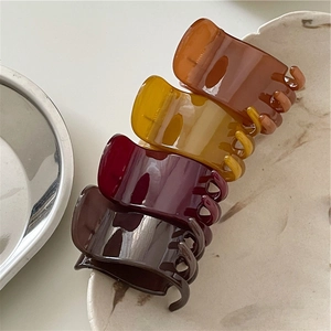 Set of four retro resin hair claws in amber and dark tones on a ceramic tray