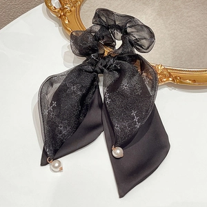 Dettaglio dell'elastico in organza nera con perle eleganti e nastro a fiocco