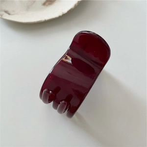 Close-up of a polished dark wine red resin hair claw clip with glossy finish