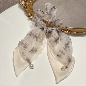 Dettaglio dell'elastico in tulle floreale con nastri lunghi e ciondoli di perle eleganti