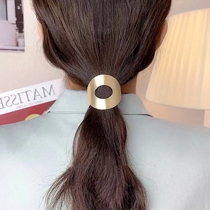 Détail d'un élastique à cheveux doré brossé sur une queue de cheval dans un décor moderne