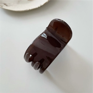 Detail of amber tortoiseshell hair claw clip made of glossy resin in dark brown finish