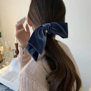 Detailed back view of a navy velvet bow hair clip worn on long hair for French style