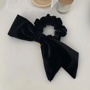 Elegant black velvet bow hair scrunchie with a gold metal pendant on white background