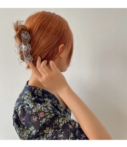 Detailed view of a transparent rose claw clip on model with floral chiffon blouse