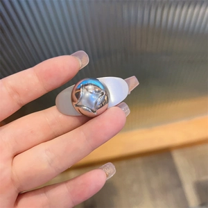Detail of a white hair clip featuring a silver metallic sphere with star engraving