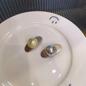 Detail view of gold and silver teardrop hair clips with star cutout on a white ceramic plate