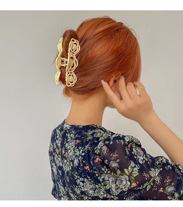 Detail of cream rose cutout hair claw clip shown on model with elegant French style hair