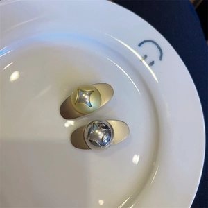 Detail view of two-tone metal teardrop hair clips with engraved four-point star patterns