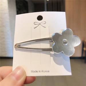 Gros plan détaillé d'une pince à cheveux fleur argentée avec texture métal brossé