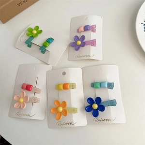 Detail of candy-colored flower and square resin hair clips set on white card packaging