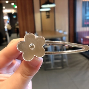 Gros plan sur la pince à cheveux en métal argenté avec motif de fleur à effet miroir