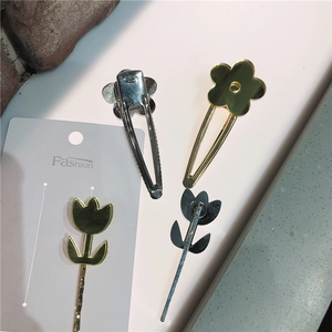 Détail de quatre barrettes à cheveux en métal avec fleurs et tulipes sur carte mode