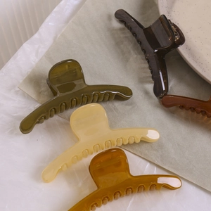 Détail de grandes pinces à cheveux en résine vert olive et ambre pour coiffure mi-haute