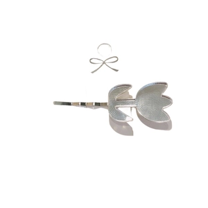 Pince à cheveux tulipe argentée sur carte à nœud blanc au style minimaliste