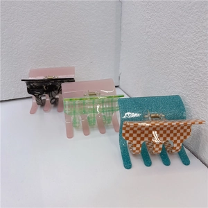 Detailed close-up of three colorful checkered acetate hair claws with metallic springs