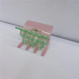 Detail view of pink and green checkerboard acetate hair claw clip with metal spring