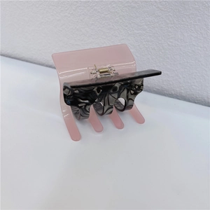 Macro detail of large checkerboard hair claw clip with pink and marble texture