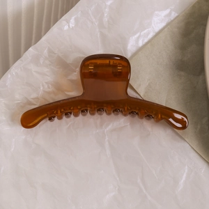 Détail d'une pince à cheveux élégante en résine ambrée avec une finition polie brillante