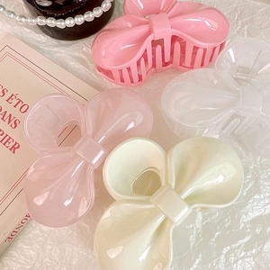 Gros plan de quatre pinces à cheveux en forme de nœud en rose, blanc et crème sur papier texturé