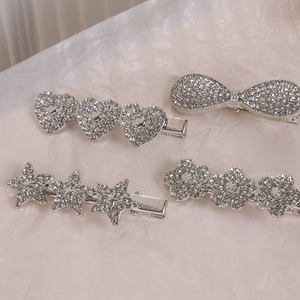 Détail de barrettes argentées avec strass brillants en formes d'étoile et de cœur