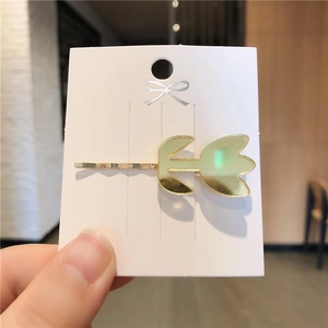 Pince à cheveux dorée en forme de tulipe avec effet miroir sur une carte de support
