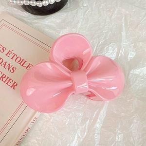 Gros plan d'une pince à cheveux rose brillante avec un nœud en résine sur un livre décoré