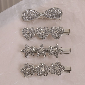 Détail de quatre pinces à cheveux argentées avec strass en formes de nœud, cœur et étoile